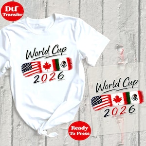 May include: White t-shirt with a "World Cup 2026" design. The design features the flags of the United States, Canada, and Mexico. The words "Dtf Transfer" and "Ready To Press" are also visible.