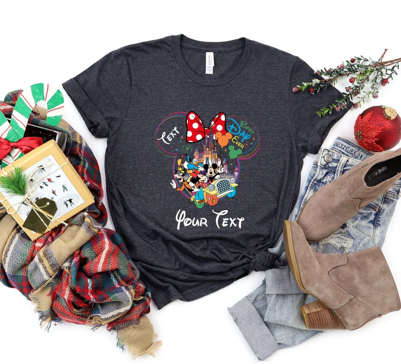 May include: Dark gray t-shirt featuring a colorful graphic of Disney characters, including Mickey and Minnie Mouse, with the text "Best Day Ever" and "Your Text". The design includes a red polka dot bow.