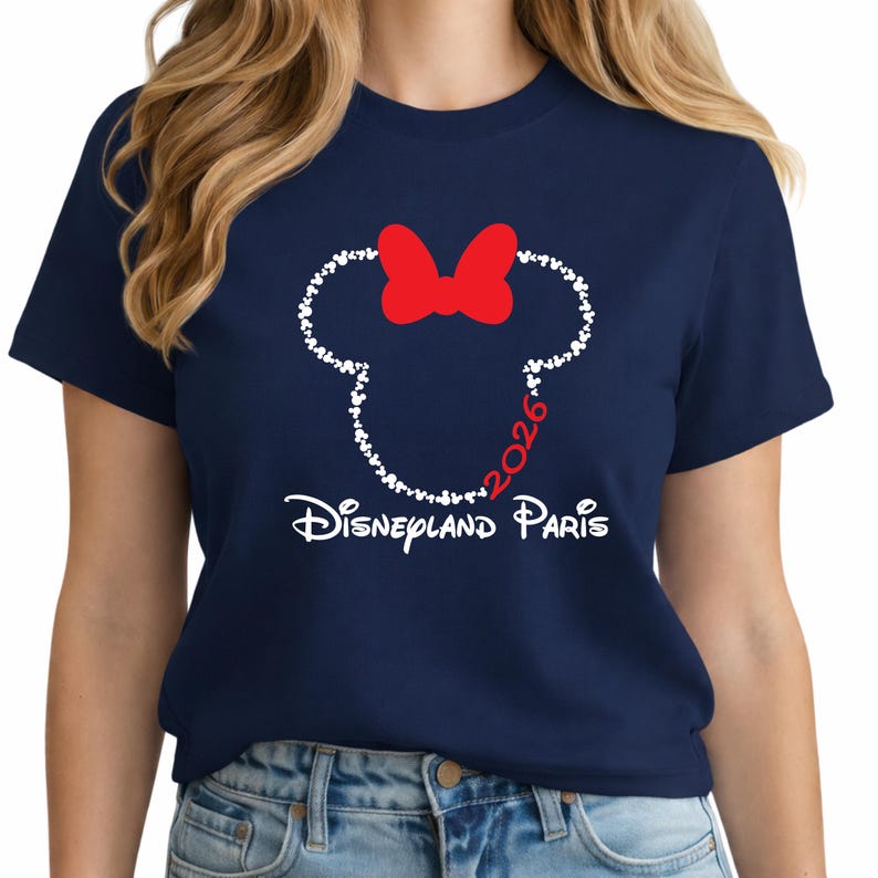 May include: Navy blue t-shirt featuring a white outline of a mouse head made of small hearts, with a red bow. The text "2026" is inside the head, and "Disneyland Paris" is written below in white.