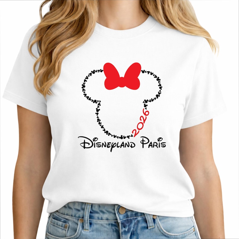 May include: White t-shirt featuring a Minnie Mouse design. The design includes a red bow, a silhouette of Minnie's head made of black dots, and the text "Disneyland Paris 2026" in black and red.