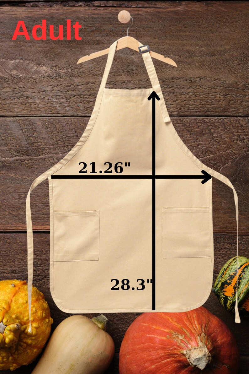 May include: A beige apron with two pockets, hanging on a wooden hanger. The apron measures 21.26 inches wide and 28.3 inches long. The word "Adult" is in red at the top. Gourds are at the bottom.