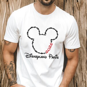 May include: White t-shirt featuring a black Mickey Mouse head outline made of small hearts. The number "2026" is in red, and the words "Disneyland Paris" are printed below the graphic in black.