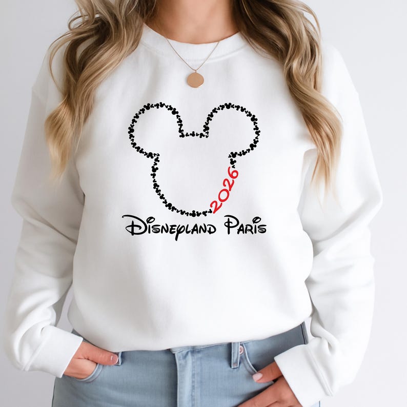 May include: White sweatshirt featuring a Mickey Mouse head outline made of small black hearts. The number "2026" is in red, and the words "Disneyland Paris" are printed below in black.