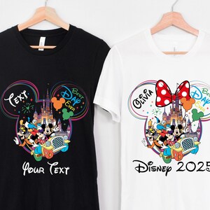 May include: Two t-shirts, one black and one white, each featuring a colorful Disney-themed graphic. The black shirt has the text "Your Text" and the white shirt says "Disney 2025". Both shirts have a Mickey Mouse head design with Disney characters.