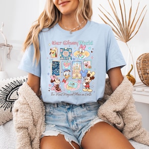 K&ouml;nnte beinhalten: Hellblaues T-Shirt mit einer farbenfrohen Grafik von Disney-Figuren und -Attraktionen. Das Design umfasst Micky Maus, Minnie Maus, Donald Duck und andere Charaktere. Der Text auf dem Shirt lautet "Walt Disney World" und "The Most Magical Place on Earth."