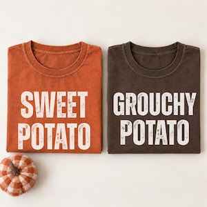 May include: Two short-sleeve t-shirts, one in burnt orange with the white text SWEET POTATO and one in dark brown with the white text GROUCHY POTATO, accompanied by a small fabric pumpkin featuring a white and orange checkered pattern.
