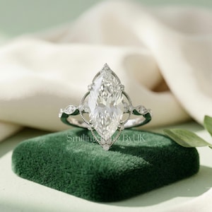 Custom marquise engagement ring featuring a stunning floral halo design. Personalized 14k solid gold band highlighting an elongated lab grown diamond. This bespoke vintage inspired jewelry piece captures affordable luxury perfectly. Trending sustainable lab stone, art deco aesthetic, statement piece, handmade USA style, ethical bridal gem, and brilliant cut bridal wedding set.