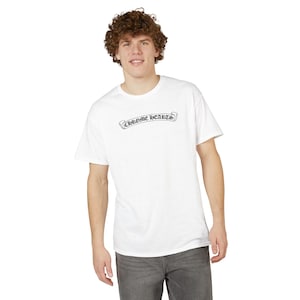 May include: White t-shirt with the text "CHROME HEARTS" in a black banner design across the chest. The shirt is a classic crew neck style and is being worn by a person.