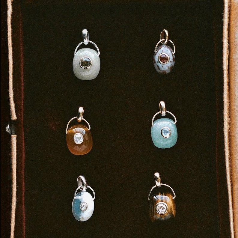 Puede incluir: Seis colgantes de piedras preciosas con herrajes de metal dorado y plateado. Los colgantes presentan varios colores, incluyendo verde claro, marr&oacute;n, azul y blanco. Cada colgante tiene una forma de piedra &uacute;nica y una peque&ntilde;a piedra de acento redonda.