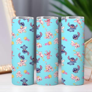 May include: Three cylindrical tumblers with a light blue background featuring a repeating pattern of blue and pink cartoon characters. Each tumbler has a metallic silver rim at the top and displays various poses of the characters scattered across the surface.