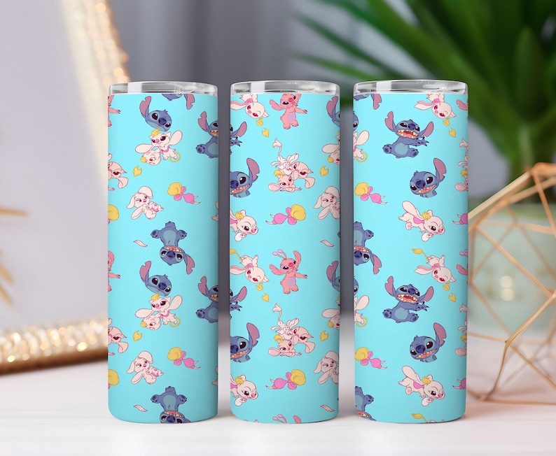 May include: Three cylindrical tumblers with a light blue background featuring a repeating pattern of blue and pink cartoon characters. Each tumbler has a metallic silver rim at the top and displays various poses of the characters scattered across the surface.