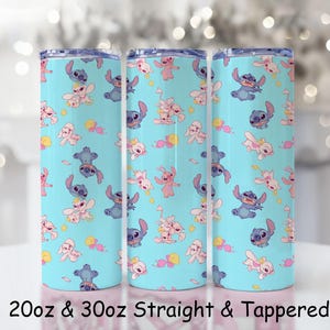 May include: Three cylindrical tumblers with a light blue background featuring a repeating pattern of blue and pink cartoon characters. The text at the bottom reads 20oz & 30oz Straight & Tappered. Each tumbler has a silver-toned rim and a clear lid.