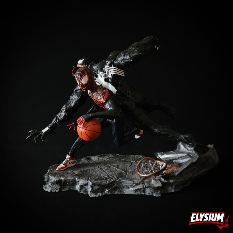 Puede incluir: Una figura din&aacute;mica que presenta a Spider-Man con un traje rojo y negro botando un bal&oacute;n de baloncesto, con Venom persigui&eacute;ndolo. Las figuras est&aacute;n posadas sobre una base rocosa. La palabra "ELYSIUM" est&aacute; en la esquina inferior derecha.
