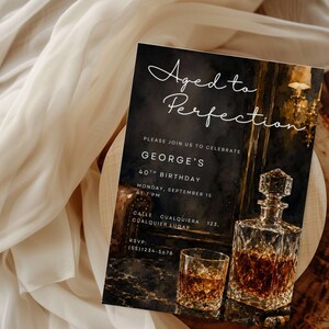 May include: Aged to Perfection birthday invitation with a whiskey decanter and glass. The invitation features the text "Aged to Perfection" in elegant script. The invitation includes details for George's 40th birthday.