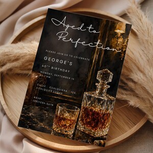 May include: Aged to Perfection birthday invitation card featuring a whiskey decanter and glass. The invitation includes the text "Aged to Perfection" and details for George's 40th birthday, including the date, time, and location.