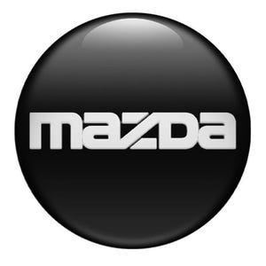 Könnte beinhalten: Ein glänzendes, schwarzes, kreisförmiges Emblem mit dem weißen Wort "MAZDA" in einer fetten, serifenlosen Schriftart. Das Logo hat einen dreidimensionalen Effekt mit einem subtilen Farbverlauf und Glanzlichtern.
