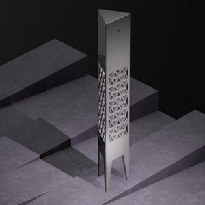 Könnte beinhalten: Eine hohe, silberne, geometrische Skulptur mit dreieckiger Spitze und rechteckigem Körper. Der Körper weist ein sich wiederholendes Dreiecksmuster auf. Die Skulptur steht auf drei Beinen und ist vor einem dunklen, abgestuften Hintergrund platziert.
