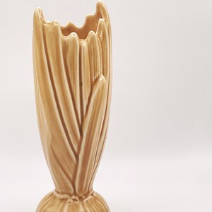 Peut inclure: Un vase en céramique beige avec un motif vertical texturé. Le vase a une base évasée et un bord supérieur ondulé. La forme générale est haute et élancée, avec une hauteur d'environ 25 cm.