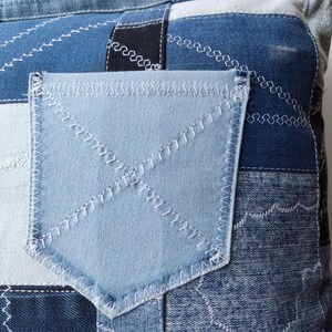 Pu&ograve; includere: Primo piano di un tessuto denim patchwork con una tasca azzurra. Il denim presenta varie tonalit&agrave; di blu, con dettagli di cucitura bianchi. La tasca &egrave; di una tonalit&agrave; di blu pi&ugrave; chiara ed &egrave; cucita con filo bianco.