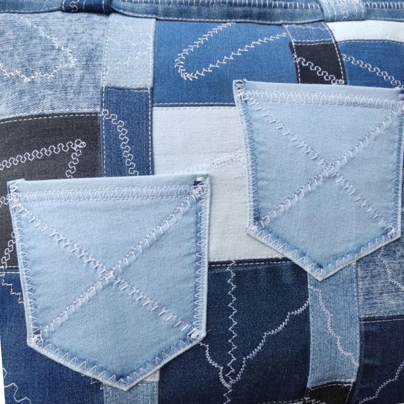 Pu&ograve; includere: Primo piano di una borsa patchwork in denim con due tasche azzurre. La borsa &egrave; realizzata con quadrati di denim blu di varie tonalit&agrave;, cuciti insieme con filo bianco. Le tasche sono anch'esse in denim azzurro, con cuciture bianche.