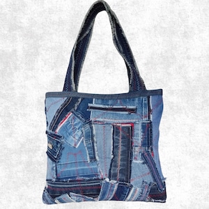 May include: A tote bag constructed from various shades of blue denim fabric patches. The bag features a rectangular shape with two shoulder straps and is decorated with visible red stitching throughout the patchwork design, creating a textured look.