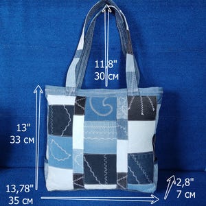 Pu&ograve; includere: Una borsa tote in denim patchwork con varie toppe di denim blu. La borsa &egrave; alta 33 cm, larga 30 cm e profonda 7 cm. Ha manici in denim e una forma rettangolare.