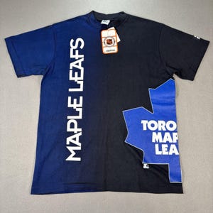 May include: A black and blue Toronto Maple Leafs t-shirt. The left side has the words "MAPLE LEAFS" in white. The right side features a blue maple leaf design with "TORO MAP LEA" in white. A Starter tag is attached.