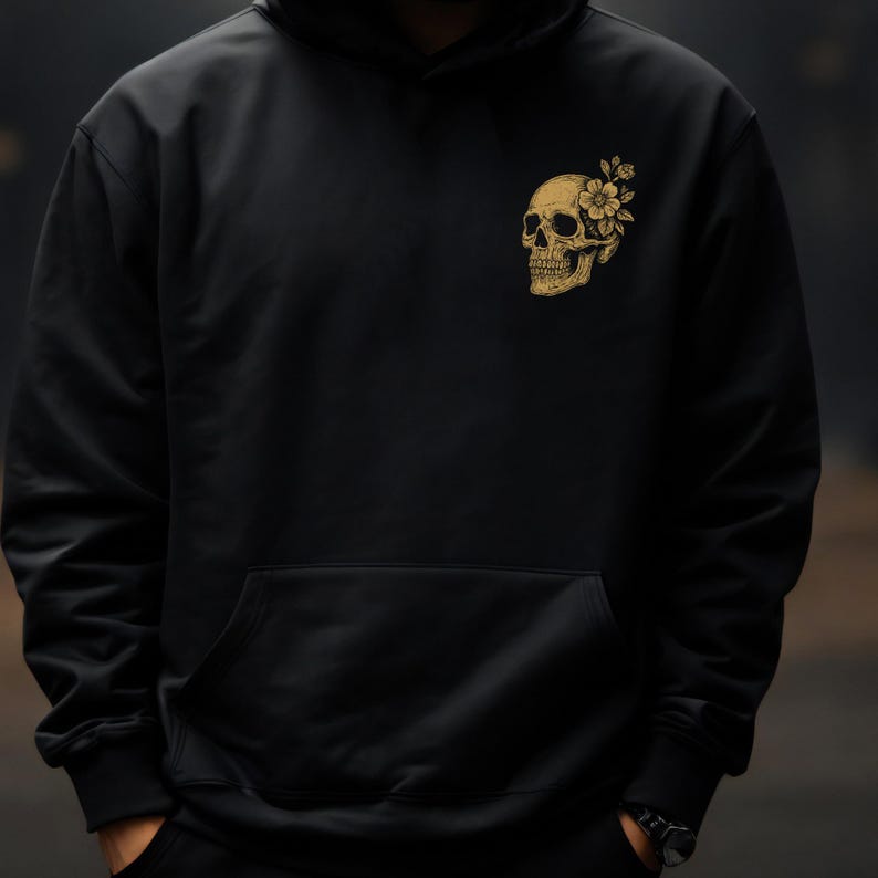 Puede incluir: Sudadera negra con un dise&ntilde;o de calavera dorada con detalles florales en el pecho izquierdo. La sudadera tiene un bolsillo delantero y una capucha con cord&oacute;n. El dise&ntilde;o combina elementos g&oacute;ticos y florales.