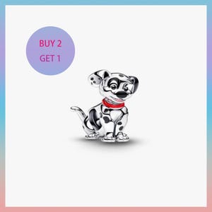 Puede incluir: Un charm de cachorro dálmata plateado con manchas negras y un collar rojo. El charm está en posición sentada. Un círculo morado con el texto "BUY 2 GET 1" está en la esquina superior izquierda.