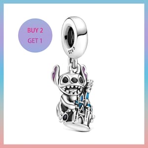 May include: A silver charm depicting Stitch holding a blue and white castle. The charm has purple detailing and the text "S925" is visible. A purple circle with the text "BUY 2 GET 1" is in the background.