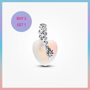 May include: A heart-shaped charm with a frosted, iridescent finish, accented with a silver-toned star and a line of clear gemstones. The charm has a silver-toned clasp. The image includes the text "BUY 2 GET 1".