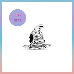 May include: A silver charm in the shape of a wizard's hat. The hat has a detailed design with a curved top and a wide brim. The charm is displayed on a white background with a purple circle that says "BUY 2 GET 1".