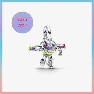 Może przedstawiać: Srebrny charms przedstawiający Buzza Astrala z Toy Story. Charms ma szczegółowy wzór postaci w jego charakterystycznym skafandrze kosmicznym, z zielonymi, fioletowymi i czerwonymi akcentami. Charms ma pętlę do przymocowania do bransoletki lub naszyjnika.