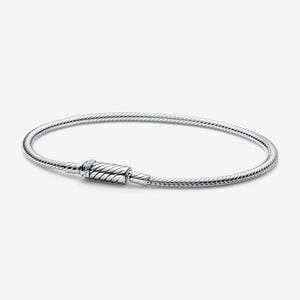 May include: A silver bracelet with a snake chain design. The bracelet features a cylindrical clasp with a textured pattern. The jewelry is displayed on a white background, highlighting its metallic shine and intricate details.