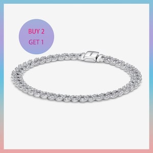 Puede incluir: Una pulsera de cadena en tono plateado con eslabones entrelazados incrustados con piedras transparentes y brillantes. La pulsera incluye un cierre rectangular con el texto Pandora grabado. Un gráfico circular muestra BUY 2 GET 1.