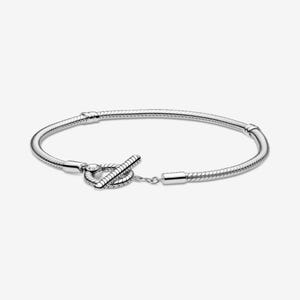 May include: A silver bracelet with a snake chain design. The bracelet features a toggle clasp closure. The clasp is a knot design with a small chain connecting to the other end of the bracelet. The bracelet is shown on a white background.