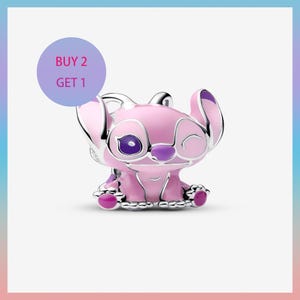 May include: A pink and purple Stitch charm with silver accents. The charm features Stitch's likeness with a winking eye and the text "BUY 2 GET 1" in a purple circle. The charm is a collectible item.