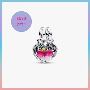 May include: A pair of silver heart-shaped charms with pink and white enamel hearts. The charms have a textured, beaded border and a small green and yellow accent. The image also includes a purple circle with the text "BUY 2 GET 1".