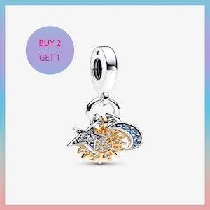 Pode incluir: Um berloque de prata com tema celestial. O berloque apresenta um design de estrela, sol e lua. A estrela e o sol têm detalhes dourados e prateados com pedras preciosas claras e azuis. O berloque tem uma argola prateada na parte superior.