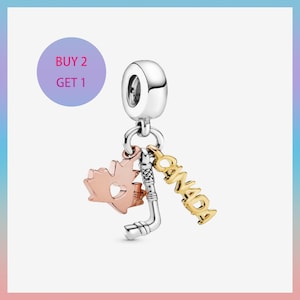 May include: A silver charm with three dangling pendants. One is a rose gold maple leaf, another is a silver hockey stick, and the third is a gold word "CANADA". A purple circle with the text "BUY 2 GET 1" is in the upper left.