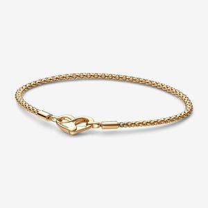 May include: A gold-colored bracelet with a textured, beaded design. The bracelet features a heart-shaped clasp. The bracelet is approximately 7 inches in length.