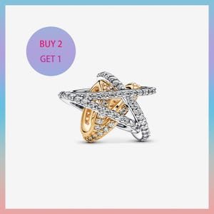 May include: A star-shaped charm with a gold centre and silver bands encrusted with small, clear gemstones. The charm has a Buy 2 Get 1 promotion in a purple circle.