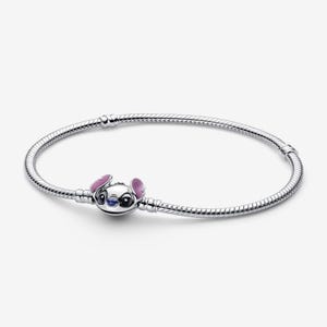 Puede incluir: Una pulsera de plata con un charm del personaje Stitch de Disney. El charm est&aacute; detallado con esmalte azul, rosa y blanco. La pulsera tiene un dise&ntilde;o de cadena de serpiente.