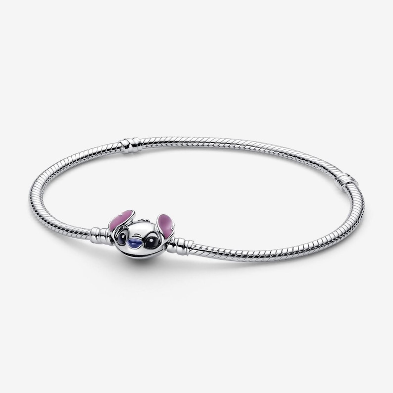 Puede incluir: Una pulsera de plata con un charm del personaje Stitch de Disney. El charm est&aacute; detallado con esmalte azul, rosa y blanco. La pulsera tiene un dise&ntilde;o de cadena de serpiente.