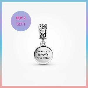 May include: A silver charm with a decorative top and a round pendant. The pendant is engraved with the words "You are my Happily Ever After". The charm is suspended from a decorative bail. The image also includes a purple circle with the text "BUY 2 GET 1".