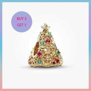 May include: A gold Christmas tree charm with a star. The charm is decorated with red and green gemstones. The text "BUY 2 GET 1" is in a purple circle in the upper left corner.