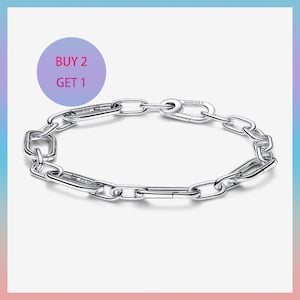 Puede incluir: Una pulsera de eslabones en tono plateado con eslabones rectangulares alargados y un cierre seguro. La superficie metálica es pulida y reflectante. Un círculo morado en la esquina superior izquierda muestra el texto BUY 2 GET 1.