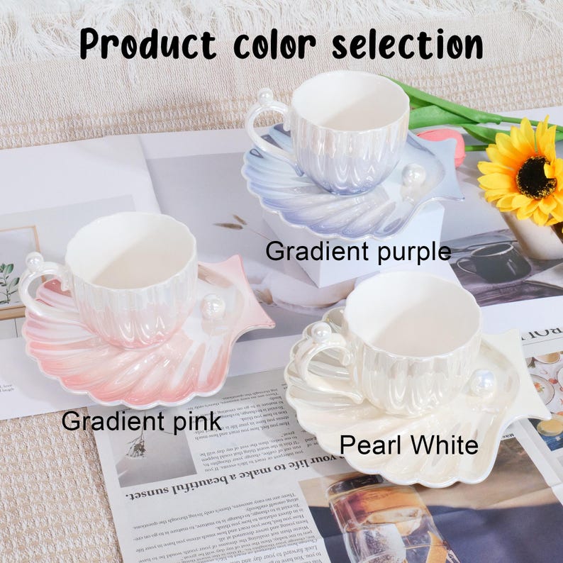 May include: A set of three ceramic teacups and saucers in gradient pink, gradient purple, and pearl white. Each cup has a pearl accent on the handle and sits on a seashell-shaped saucer. The text "Product color selection" is at the top.