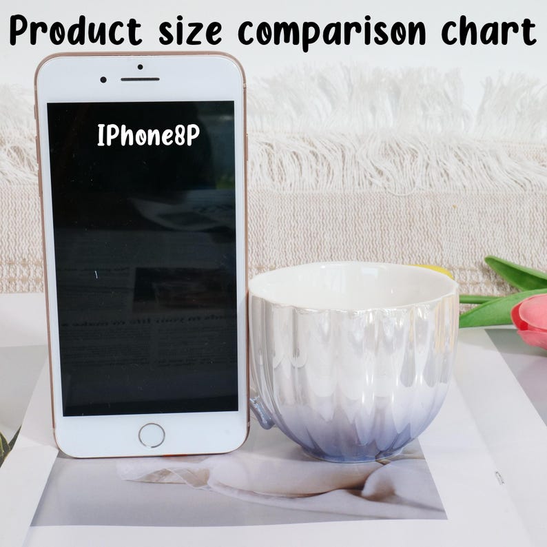 May include: A product size comparison chart featuring an iPhone 8P next to a pearlescent white and blue ceramic mug. The mug has a wavy design and a small handle. The text "Product size comparison chart" is at the top.