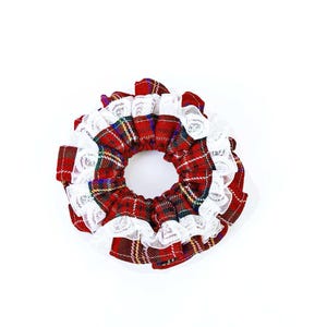 Puede incluir: Una goma para el pelo a cuadros rojos con ribete de encaje blanco. El accesorio para el cabello presenta un patrón de cuadros tradicional en rojo, verde, amarillo y azul. El encaje blanco añade un delicado contraste a la tela a cuadros.